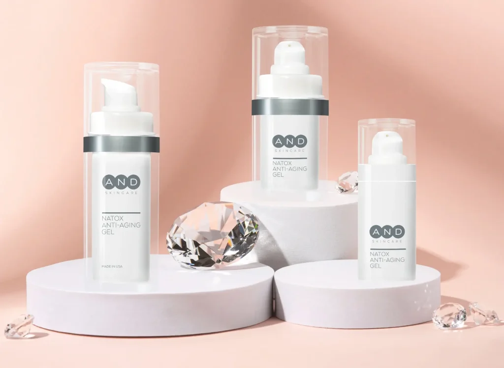 AND Skincare NATOX Anti-Aging-Gel in drei weissen Pumpflaschen auf Sockeln