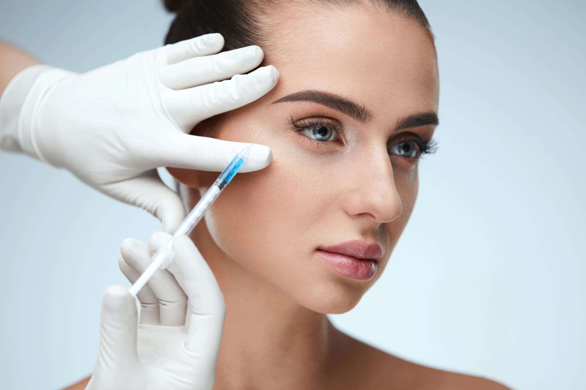 Skinbooster-Behandlung: feine Kanüle mit Hyaluronsäure an Wange und Schläfe