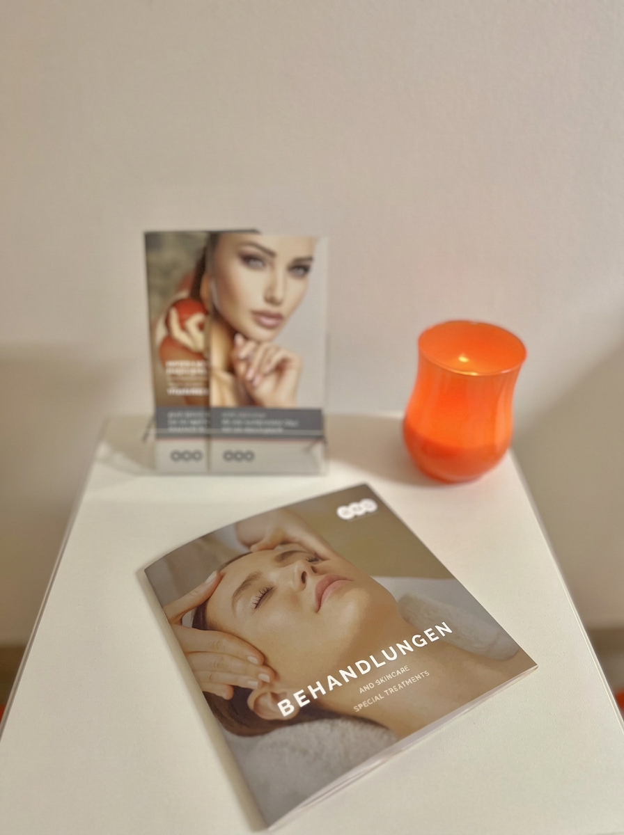 Eingangsbereich im Be Skin® Institut mit Behandlungsbroschüre und oranger Kerze